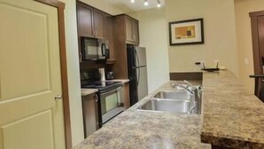 A kitchen with granite countertops, stainless steel appliances, and wooden cabinets.