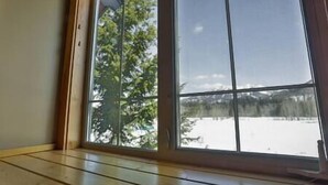 A room with a large window overlooking a snowy landscape with trees. - Alpine Chalet / Hot Tub / Garage (Fernie)