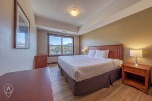 Una habitación de hotel con una cama grande, mesitas de noche, un escritorio y una ventana con vistas.