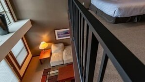 A bedroom with a bed, a nightstand, a lamp, and a small table.