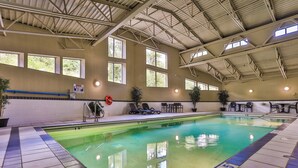 Une piscine intérieure à l’eau claire, dotée d’un sol carrelé et d’une structure de toit.
