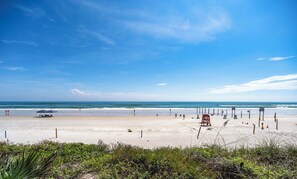 A beach with a lifeguard tower, umbrellas, and beach chairs.