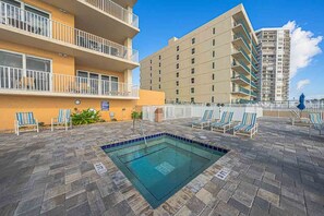 A rooftop pool area with lounge chairs and a swimming pool. - Panoramic Views! Luxury 10th Floor Condo at Sanibel Condominium #1001 (Daytona Beach Shores)