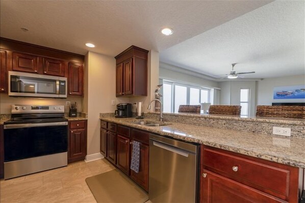 A modern kitchen with granite countertops, stainless steel appliances, and wooden cabinets.