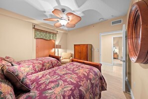 Ein Schlafzimmer mit zwei Betten, einem Deckenventilator, einem Holzschrank und einer Tür zu einem anderen Raum.