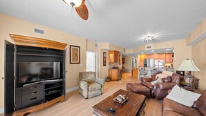 A spacious living room with a large entertainment center, leather sofas, and a dining area in the background.