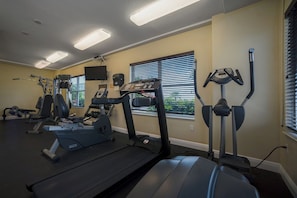 Un gimnasio con cintas de correr, elípticas y equipo de pesas.