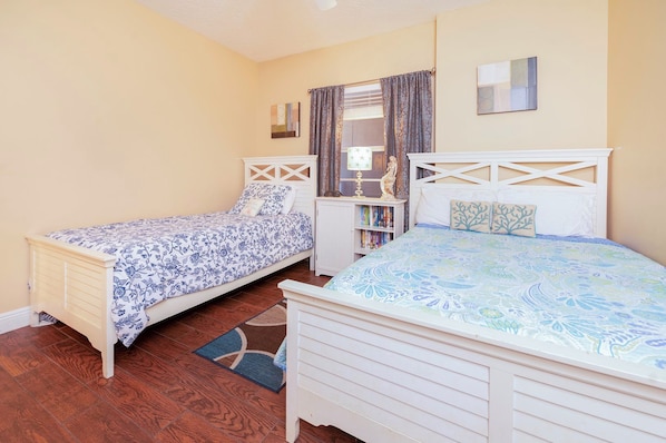 Un dormitorio con dos camas, una estantería, un espejo y una ventana con cortinas.