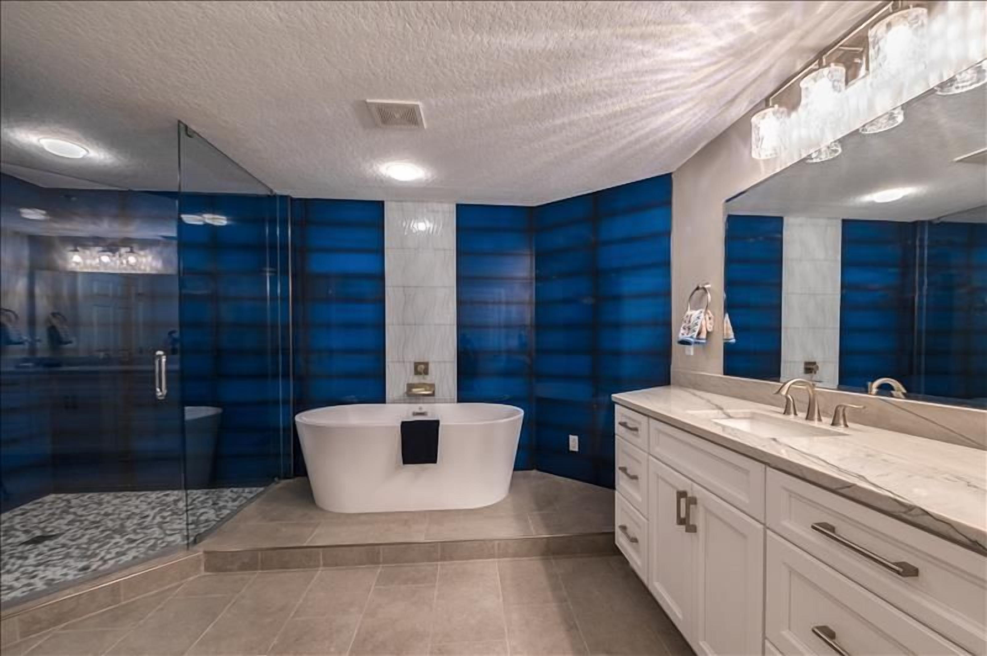 Un baño moderno con una bañera independiente, un espejo grande y una ducha a ras de suelo.