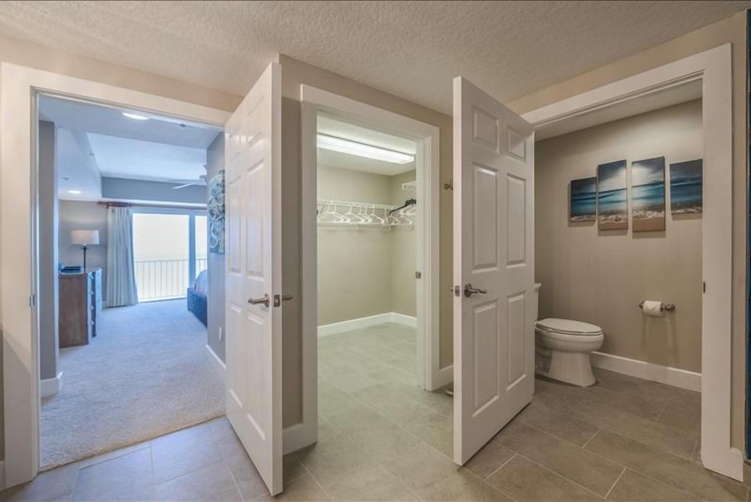 A modern bathroom with a toilet, a shower area, and a walk-in closet with a white door.