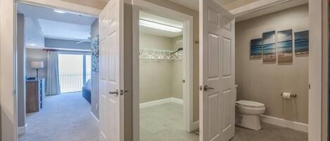 A modern bathroom with a toilet, a shower area, and a walk-in closet with a white door.