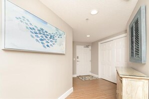 A hallway with a white door, a wooden cabinet, and a large abstract painting on the wall.