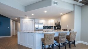 A modern kitchen with a central island, white cabinetry, and a built-in microwave.