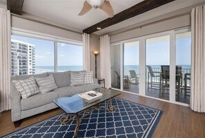 Relax in this stylish living room with a sofa, coffee table, and ocean views from the balcony.