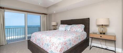 A bedroom with a large bed, a nightstand, a lamp, and a ceiling fan.
