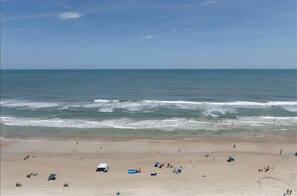 A beach with people relaxing and a few vehicles parked.