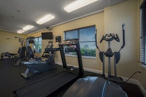 Une salle de sport équipée de tapis de course, de vélos elliptiques et de matériel de musculation.