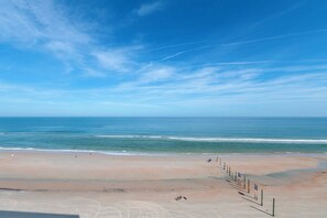 Una playa con cielo despejado, mar tranquilo y orilla arenosa.