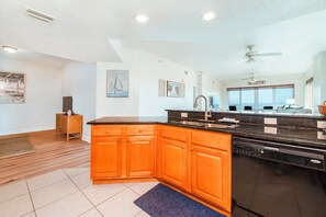 A modern kitchen with wooden cabinets, a black countertop, and a built-in dishwasher.