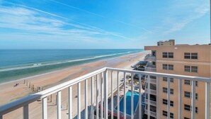 A beachfront hotel with a pool and a view of the beach and ocean.