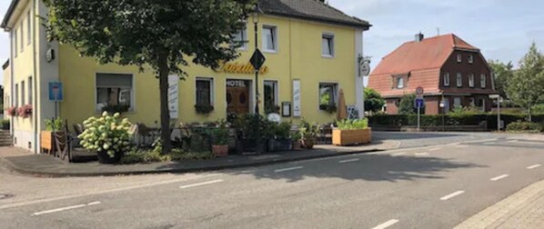 Un bâtiment jaune avec une enseigne indiquant qu’il s’agit d’un hôtel. Des plantes et des fleurs en pot sont disposées devant le bâtiment.