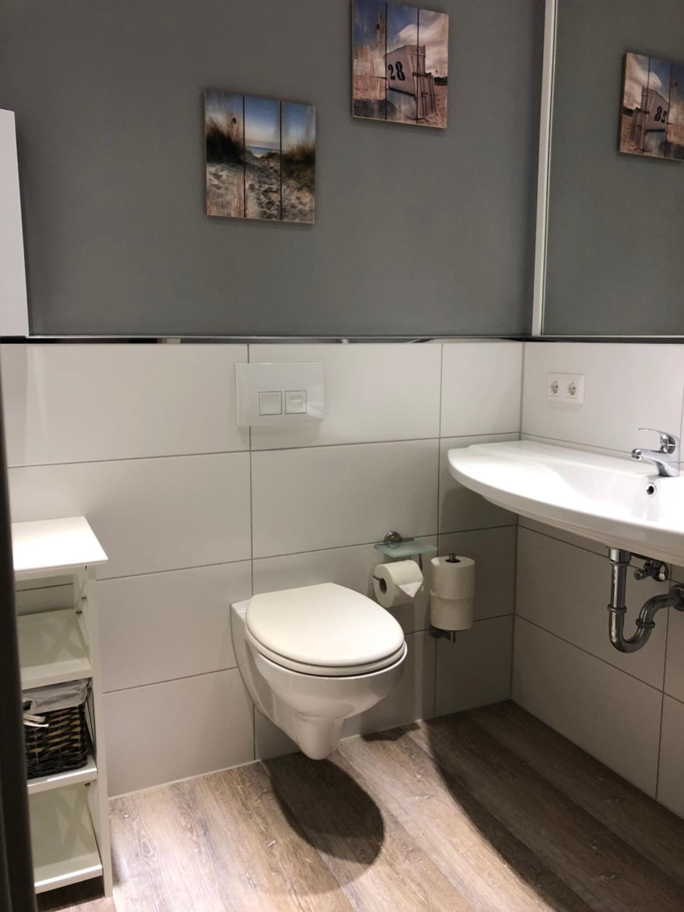 Un baño pequeño con inodoro, lavamanos y un estante.