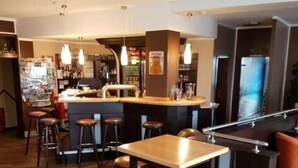 Un espace bar avec des tabourets et un comptoir, un plancher en bois et des luminaires suspendus.