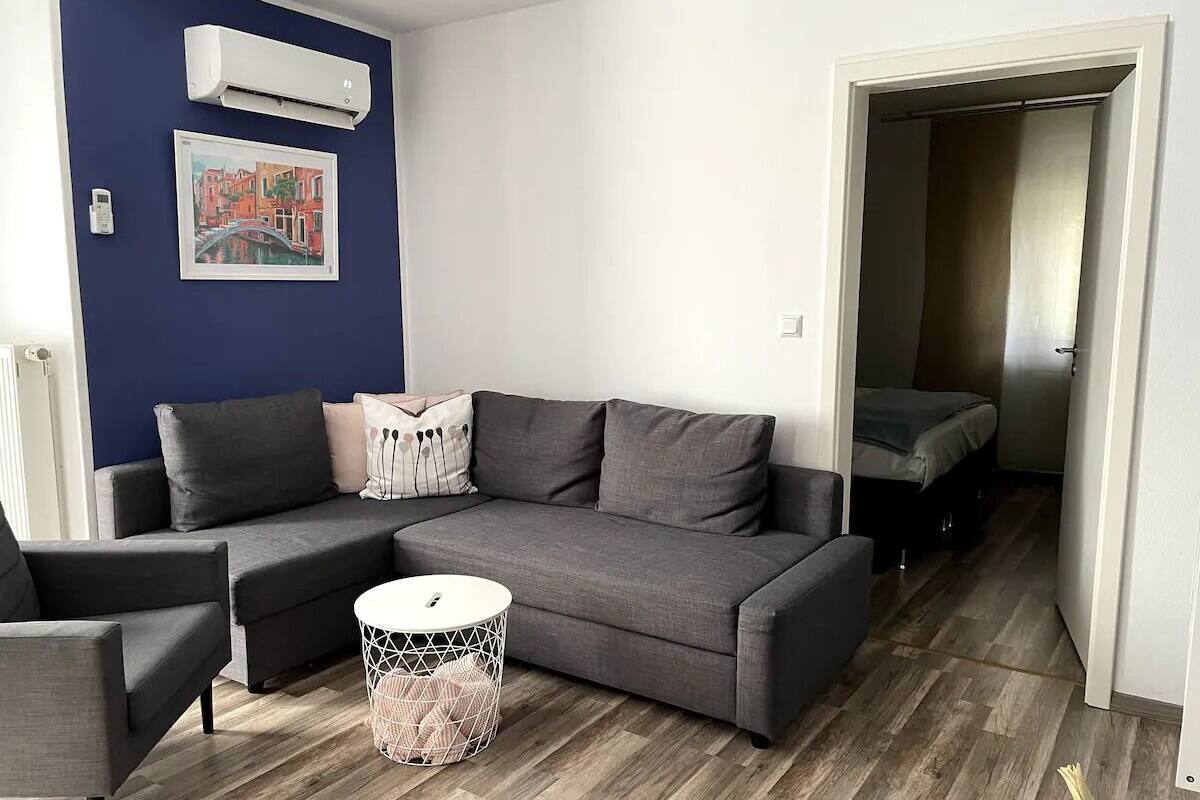 Een moderne woonkamer met een grijze hoekbank, een witte salontafel en een blauwe accentmuur.