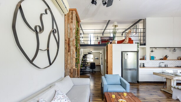 A modern living room with a sofa, coffee table, and a dining area with a wooden table and chairs. - Modern Loft Retreat with Rooftop by Sea N Rent (Tel Aviv)