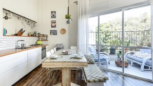A modern kitchen with white cabinets, a wooden countertop, and a dining area with a bench. There is a large window providing a view of the outdoors. - Modern Loft Retreat with Rooftop by Sea N Rent (Tel Aviv)