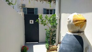 A narrow alleyway with a black gate, a potted plant, and a chair. - Home of Art in Neve-Tzedek Heart (Tel Aviv)