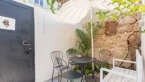 A small patio area with a black door, a white umbrella, and a table with chairs. - Home of Art in Neve-Tzedek Heart (Tel Aviv)
