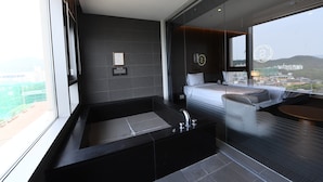 A modern bathroom with a large bathtub, a shower area, and a glass-enclosed window with a city view.