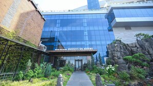 A modern building with a glass facade, a stone entrance, and a sign reading "Hotel Susung Spa Resort".