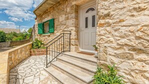 A stone building with a white door, green shutters, and a stone staircase leading to the entrance. - Holiday Home Stone Wall (Razanac)