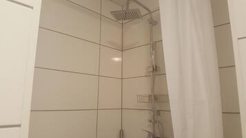 A shower with a handheld showerhead and a wall-mounted faucet.