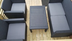 A deck with four dark wicker sofas and a matching coffee table. - Sjötorps Hostel (Sjotorp)