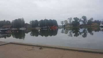 A calm lake with boats, a dock, and houses along the shore.