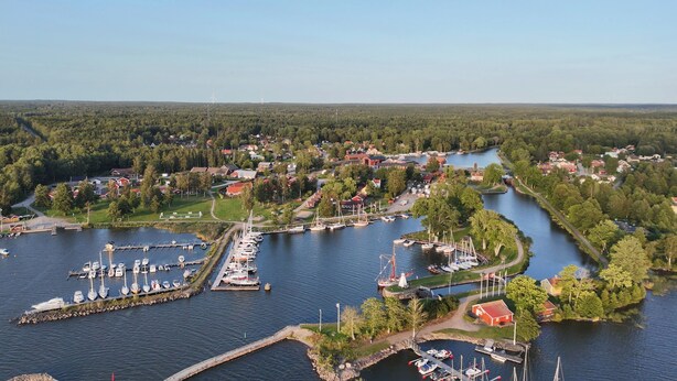 An aerial view of a lakeside village with a marina, boats, and houses. - Sjötorps Hostel (Sjotorp)