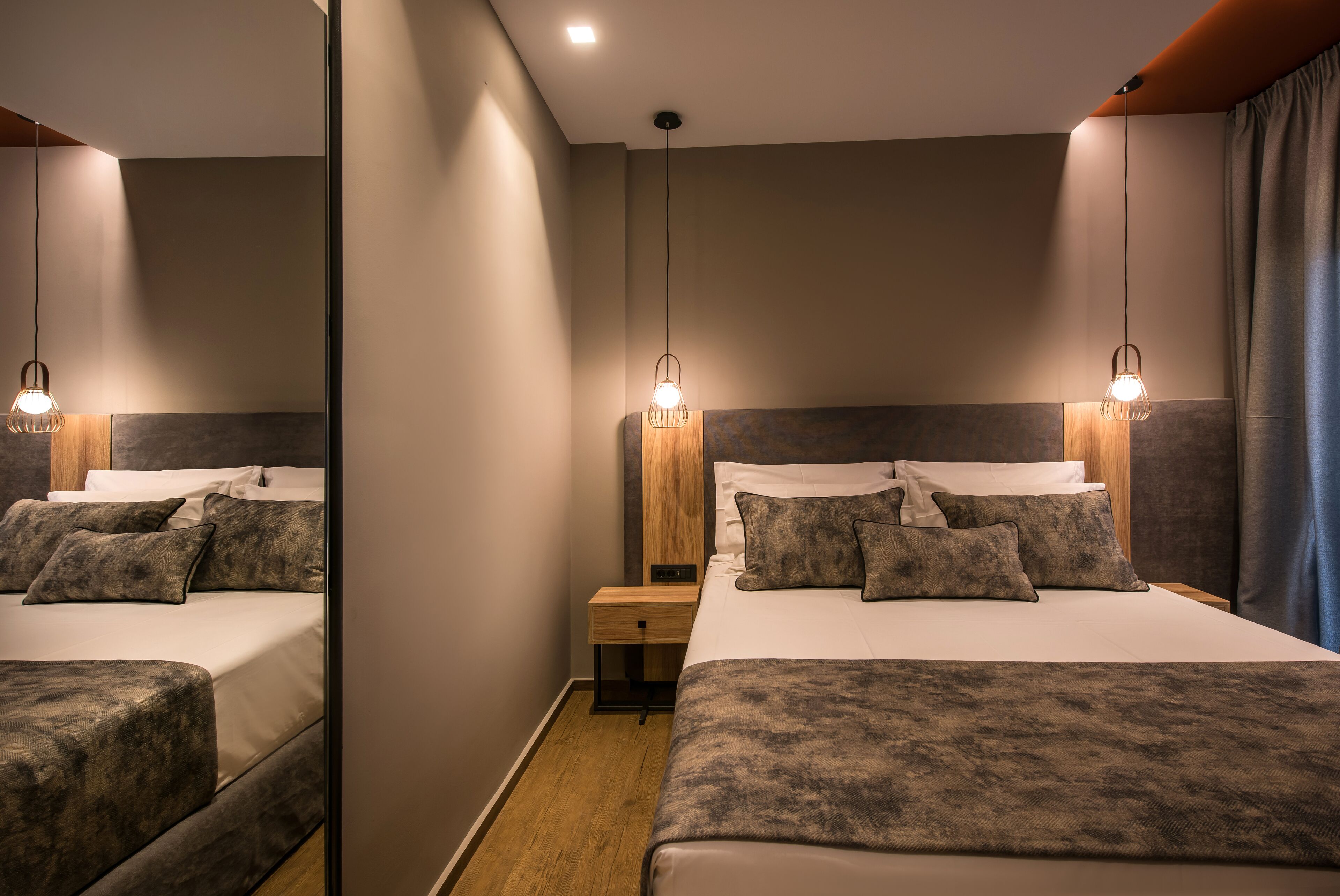 Una habitación de hotel moderna con una cama grande, dos mesitas de noche y un espejo.