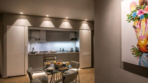 Una cocina moderna con comedor, que incluye una mesa con sillas, un cuenco de fruta y un cuadro en la pared.