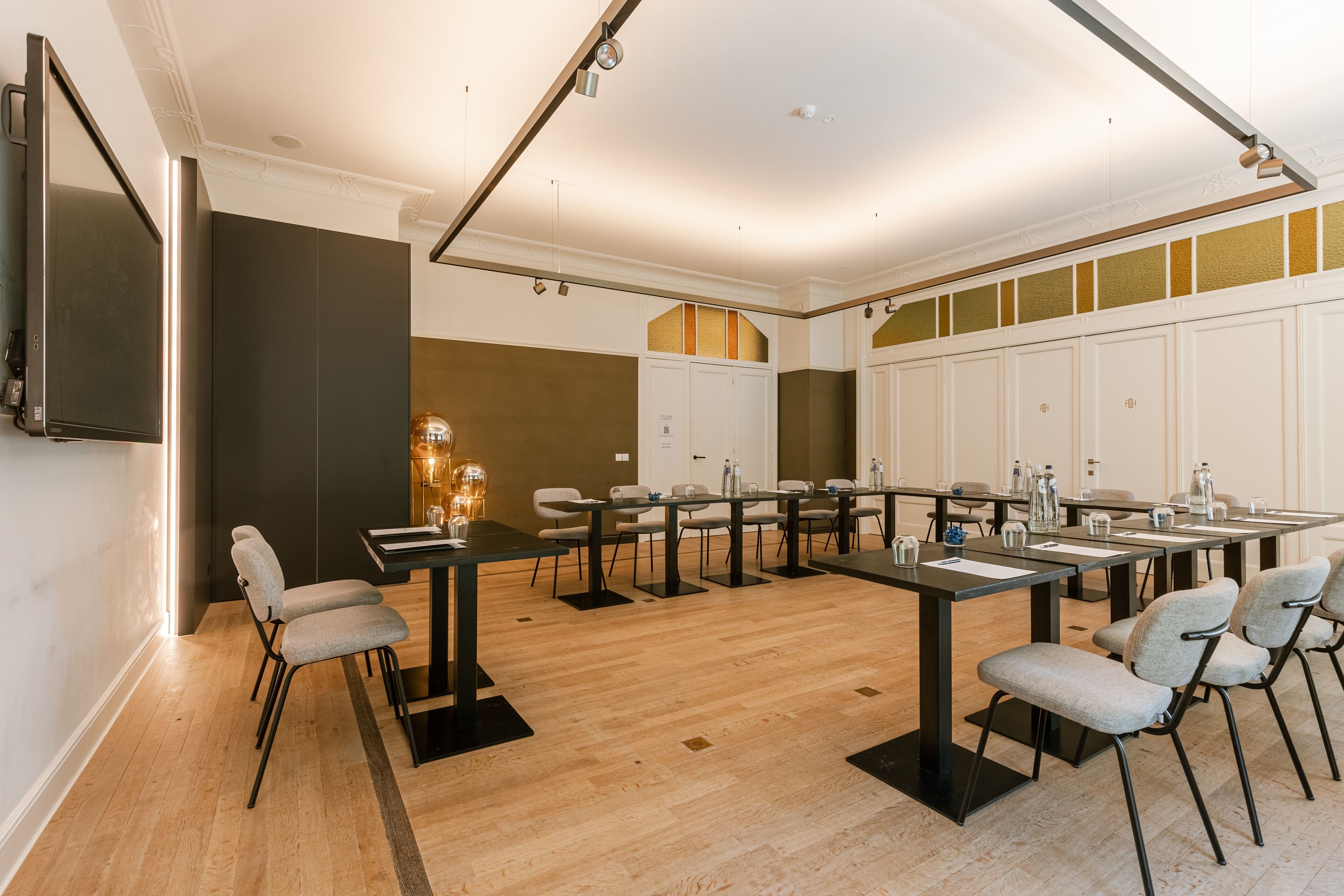 A conference room with a long table, chairs, and a flat-screen TV mounted on the wall.