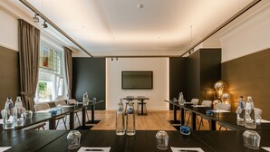 A conference room with a long table, chairs, water bottles, and a large screen. - Hotel Astoria De Haan (De Haan)