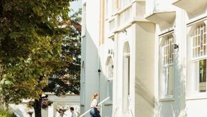 A building with a white facade, multiple windows, and a staircase leading to an upper level. - Hotel Astoria De Haan (De Haan)