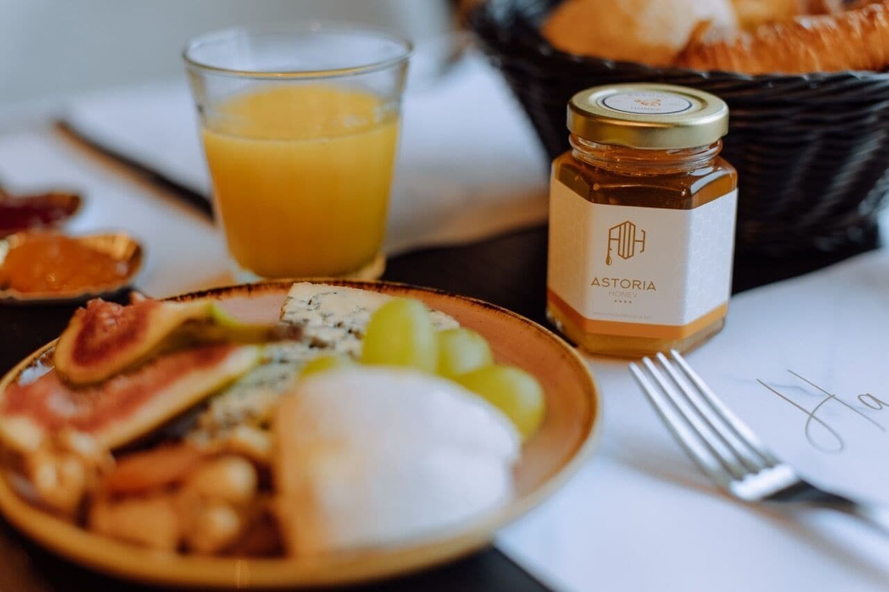 Desayuno con un plato de comida, un vaso de jugo de naranja y un frasco de miel.
