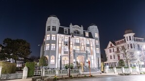 A large, historic building with a prominent sign reading "ASTORIA HOTEL" and a well-lit entrance. - Hotel Astoria De Haan (De Haan)
