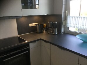 A modern kitchen with a stove, coffee maker, and kettle on the counter. - Cozy vacation home near the beach (Dornumersiel)