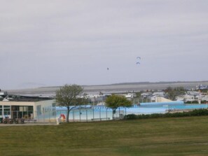 A building with a swimming pool, a fenced area, and a grassy field. - Cozy vacation home near the beach (Dornumersiel)