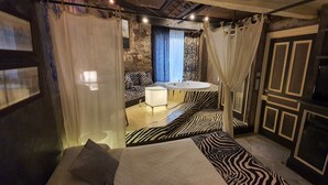 A room with a bed, a zebra-patterned bench, a white sink, and a stone wall. - Camino Real de Selores (Valle de Cabuerniga)