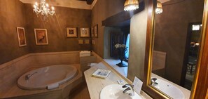 Une salle de bain avec une baignoire sur pieds, un meuble-lavabo avec un miroir et des tableaux encadrés accrochés au mur.